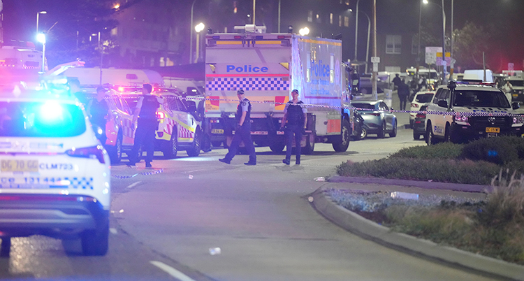 Det är kväll. På en gata i Sydney står det massor av polisbilar. Flera poliser syns också.