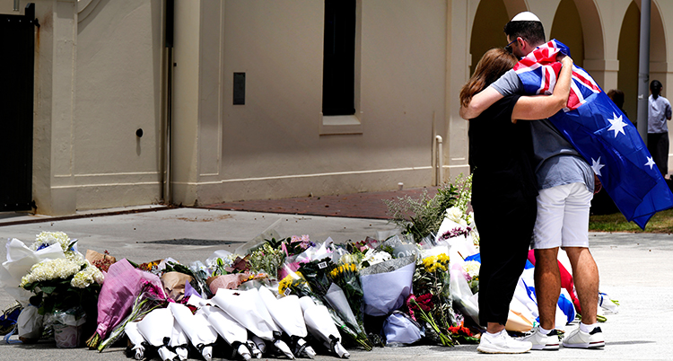 De håller om varandra. Många blommor ligger framför dem på marken.