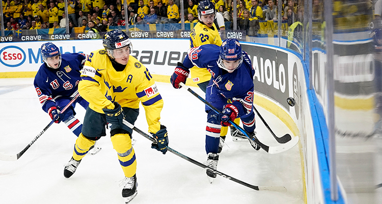 Fyra ishockeyspelare åker på isen med klubbor.