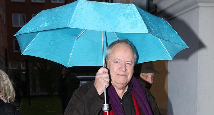 Han håller i ett paraply.