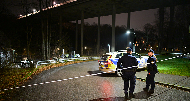 Poliser på en mörk gata med avspärrande band.