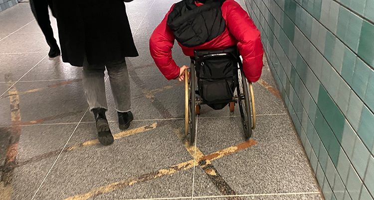 En person går, en person kör rullstol.