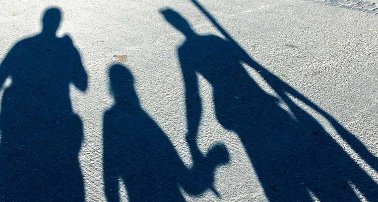 Skuggor av tre personer syns på marken.