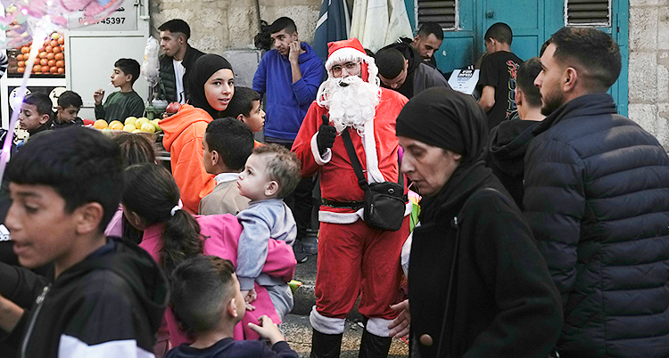 En man utklädd till tomte står bland folk i en stad.