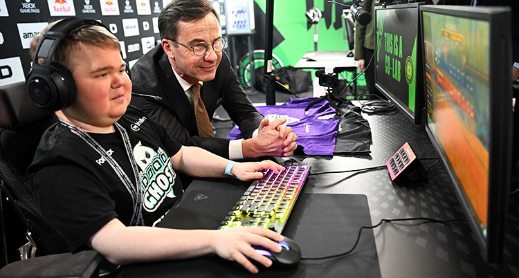 Han sitter framför en dator. Statsministern står bredvid.