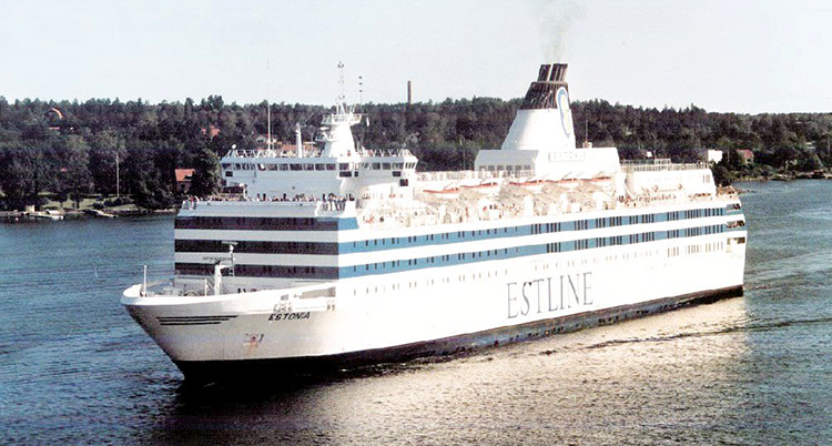 En stor färja åker på vatten. I bakgrunden syns land.