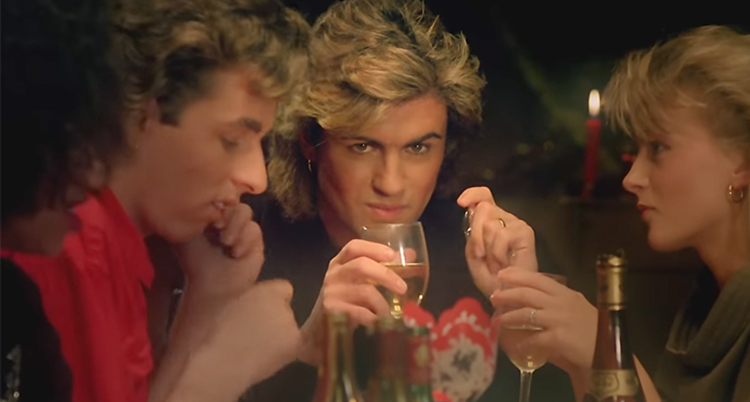 George Michael med vänner vid ett bord. Han håller ett glas.