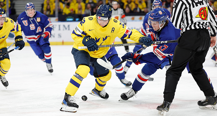Två spelare kämpar om pucken. En domare syns.