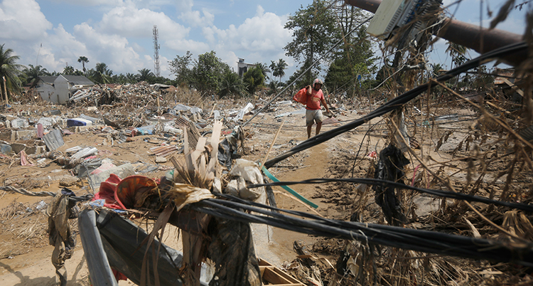Människor går bland bråte och förstörda hus.
