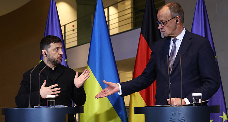 De står bredvid varandra ai varsin talarstol. Det är flaggor bakom.