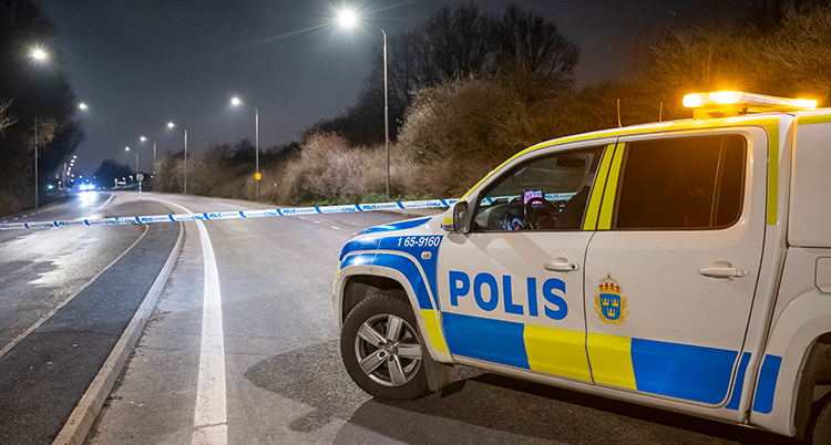 En polisbil står på en väg med ett blått band över.