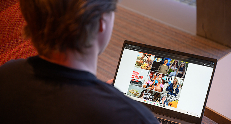 En man sitter framför en dator. På skärmen är det bilder på olika kvinnor.