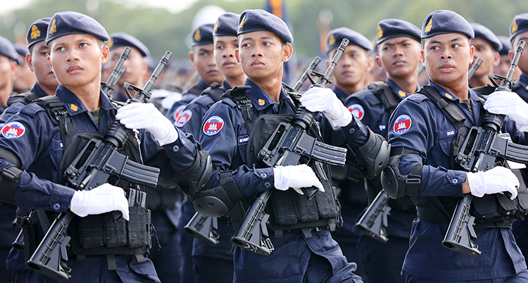 Soldater som marscherar tillsammans. De har blå uniformer, blå basker och gevär.