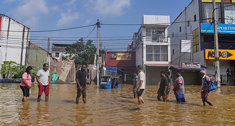 Människor står i knähögt vatten på en gata i en stad.