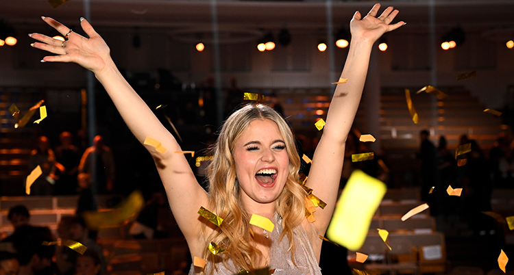 Hon är glad och sträcks upp händerna i luften.