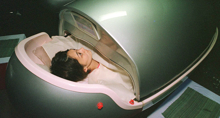 En kvinna ligger i en grej som ser ut som ett stort ägg. Det är en tvättmaskin för kroppen.