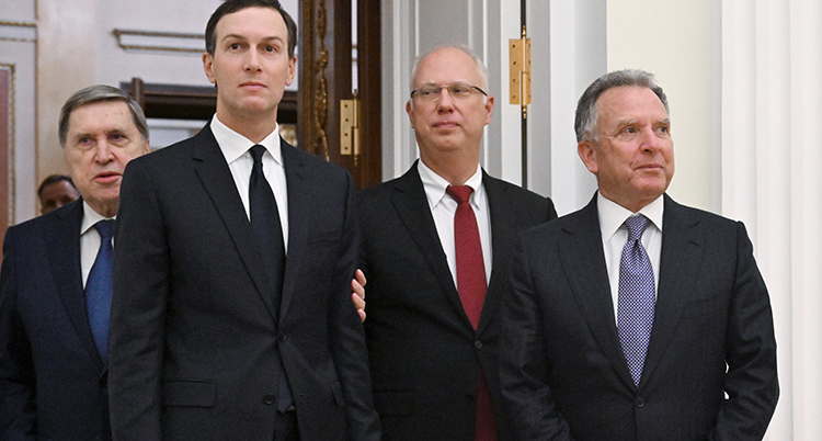 Fyra män i svarta kostymer står nära varandra.