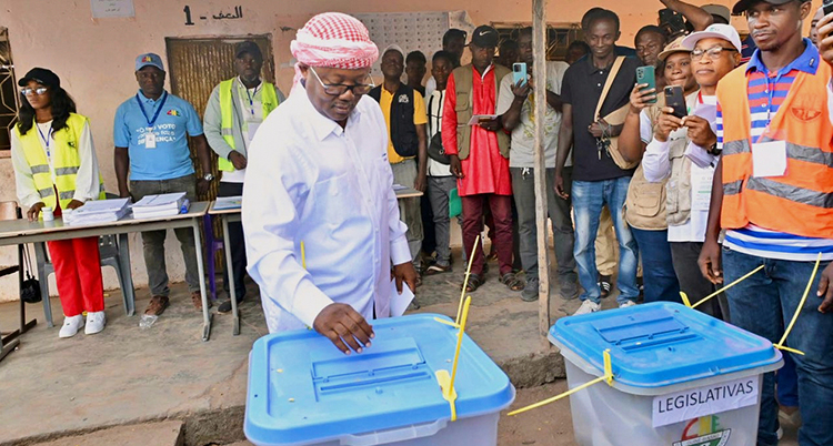 Han lägger ner en röst i en plastlåda med blått lock.