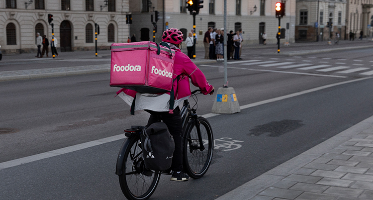 En man cyklar med en ryggsäck med mat.