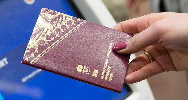 En kvinnohand som håller i ett svenskt pass.