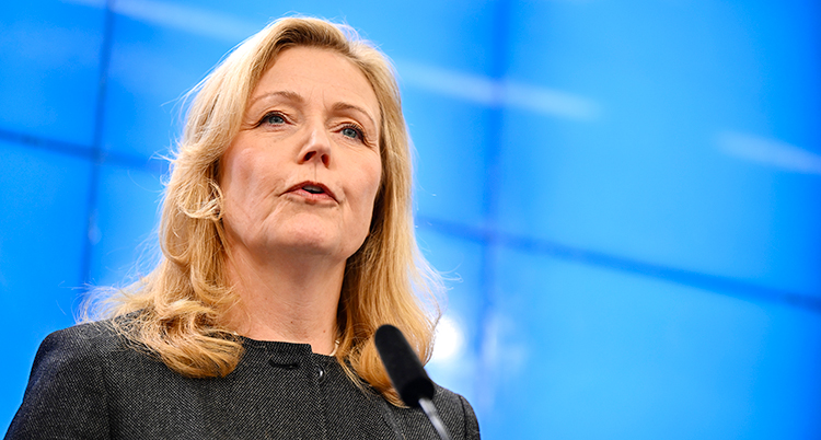 Hon står och pratar i en mikrofon på en träff med journalister.