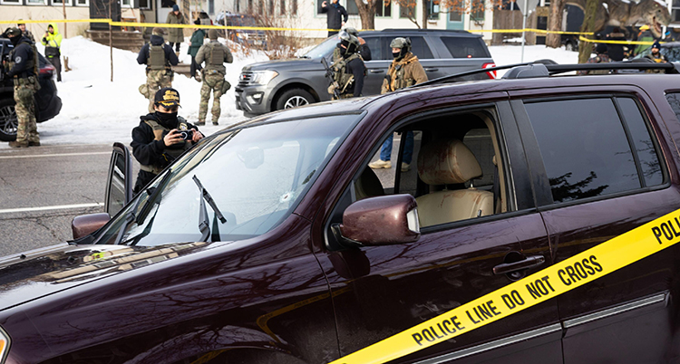 Personer med kläder som liknar militärernas står runt bilen.