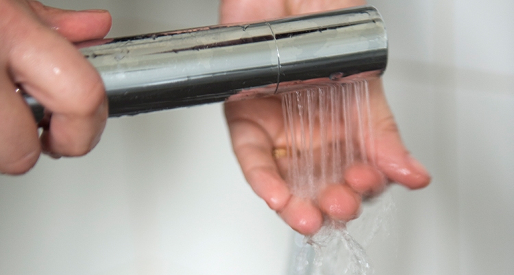 En hand känner på vattnet i en dusch.