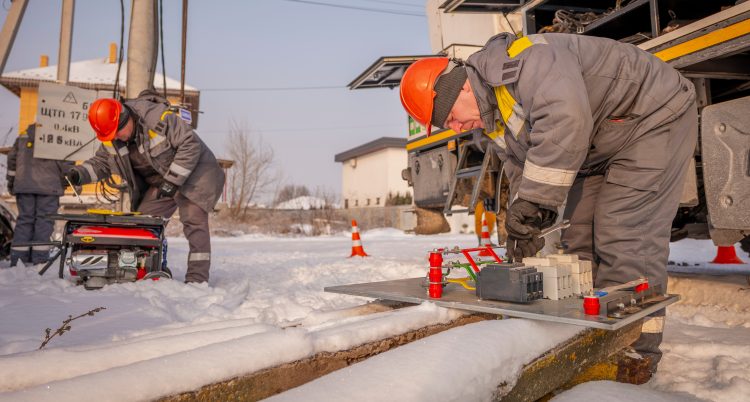 Två personer jobbar utomhus med elekrtriska system. Det är snö på marken.