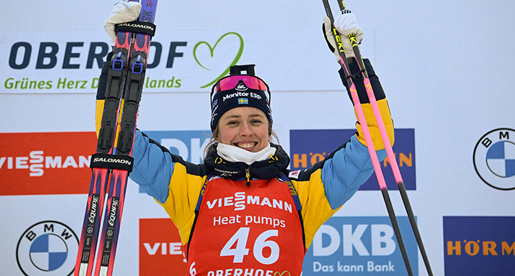 Hon håller i och lyfter upp sina skidor i en segergest.