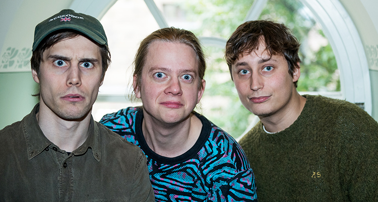 Tre unga män som tittar in i kameran.