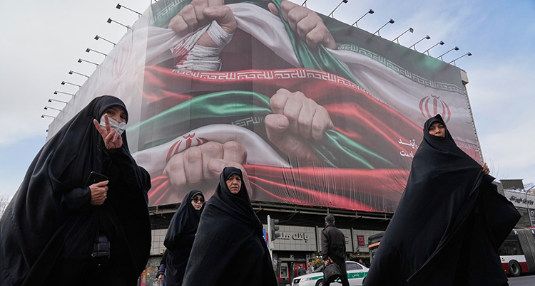 Kvinnor i heltäckande kläder går på gatan. En kvinna gör v-tecknet.