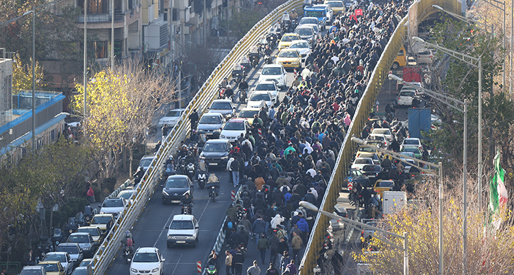 Folk går på en gata med bilar.