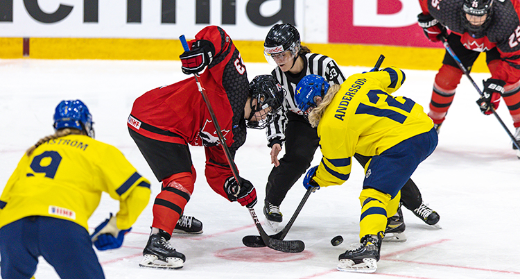 En match i ishockey. Domaren släpper ner pucken till två spelare.