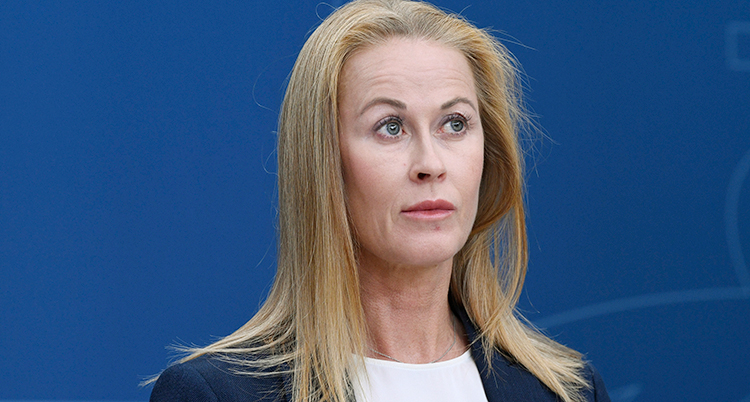 Hon ser allvarlig ut. Hon tittar åt sidan. Hon har långt hår.