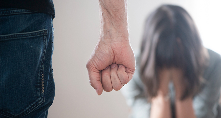 Närmast i bilden är en man med knuten näve. Längre bort i bilden sitter en kvinna med sitt ansikte i händerna.