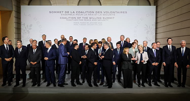 De står i en stor grupp framför en skylt.