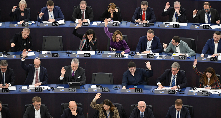 Politiker sitter i en sal. De sitter i långa rader bakom bord.