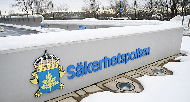 Det är snöigt. Bilden visar en låg mur utanför Säkerhetspolisens kontor. På muren står ordet Säkerhetspolisen.