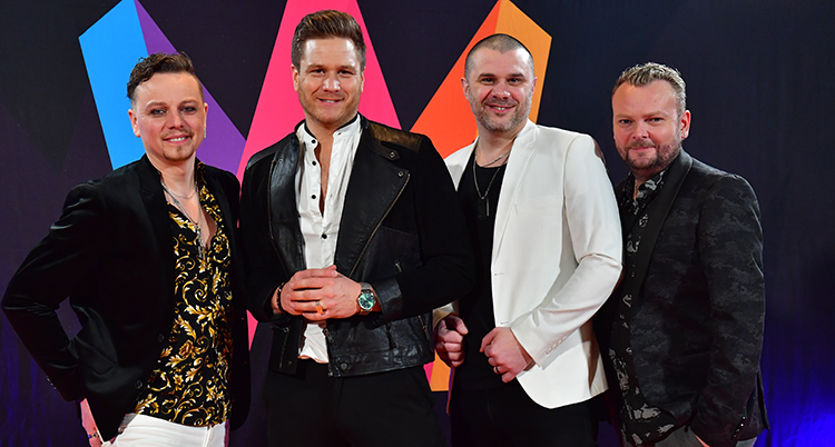 Fyra killar står på rad och ler in i kameran.