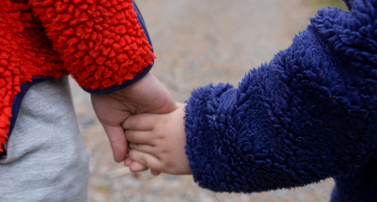 Två barn i fliströjor håller varandra i handen.