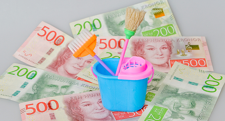 Det ligger några sedlar på ett bord. Ovanpå dem står några leksaker för städning.