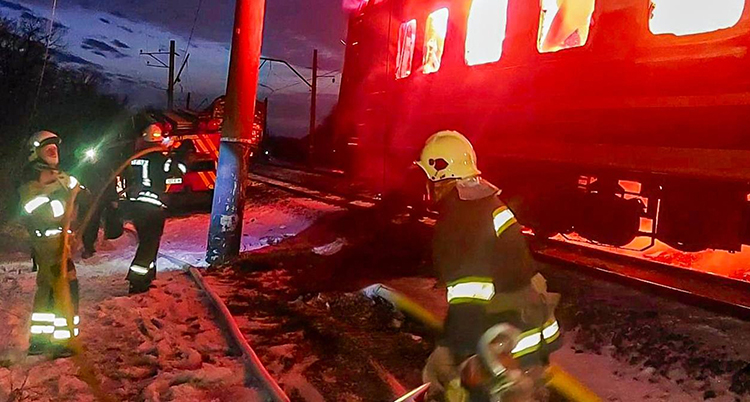 Det brinner i ett tåg. Räddningsarbetare jobbar på rälsen.