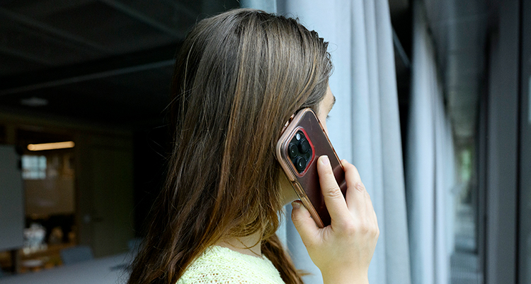 En kvinna pratar i telefon. Hon står vänd bort från kameran.