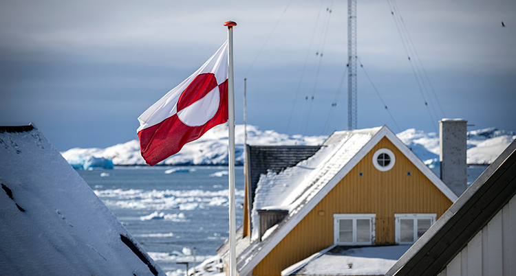Flagga är hissad bakom ett hus.