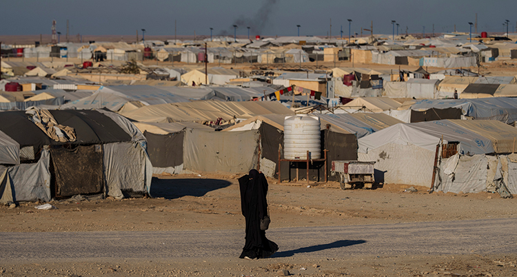 En kvinna i burka går framför flera tält.