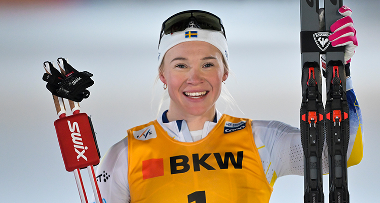 Hon håller i sina skidor och stavar.