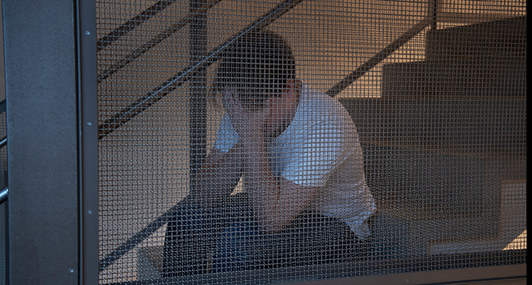 En man sitter i en trapp. Han ser ledsen ut. Han ansikte syns inte. Han håller en hand framför det.