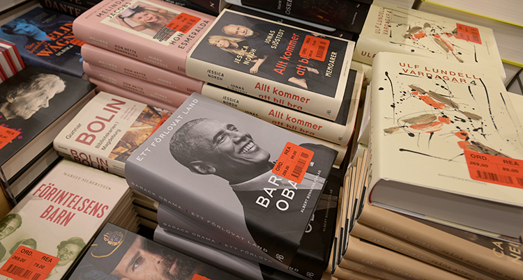 Högar med böcker. Böckerna har röda prislappar på sig.