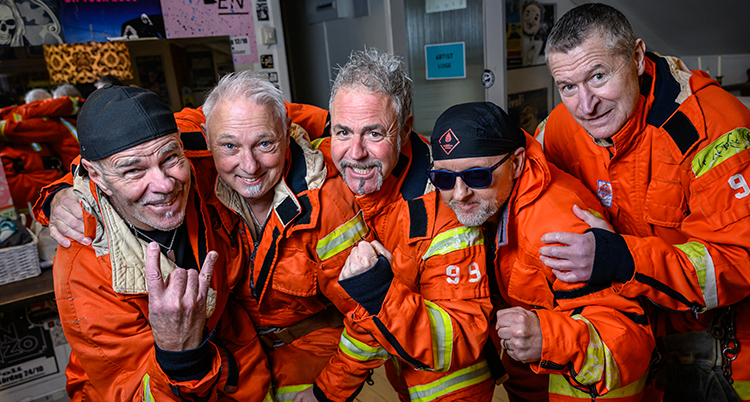 Fem brandmän håller om varandra och tittar in i kameran.