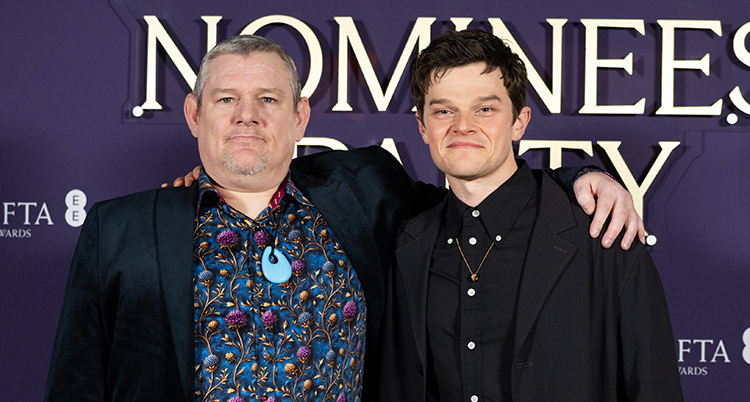 Två män håller om varandra och ler mot kameran.